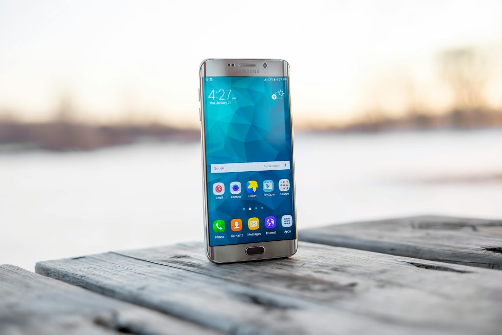 Samsung smartphone placed on a wooden surface outdoors during sunset.Mobile World Bangladesh Mobile World Bangladesh